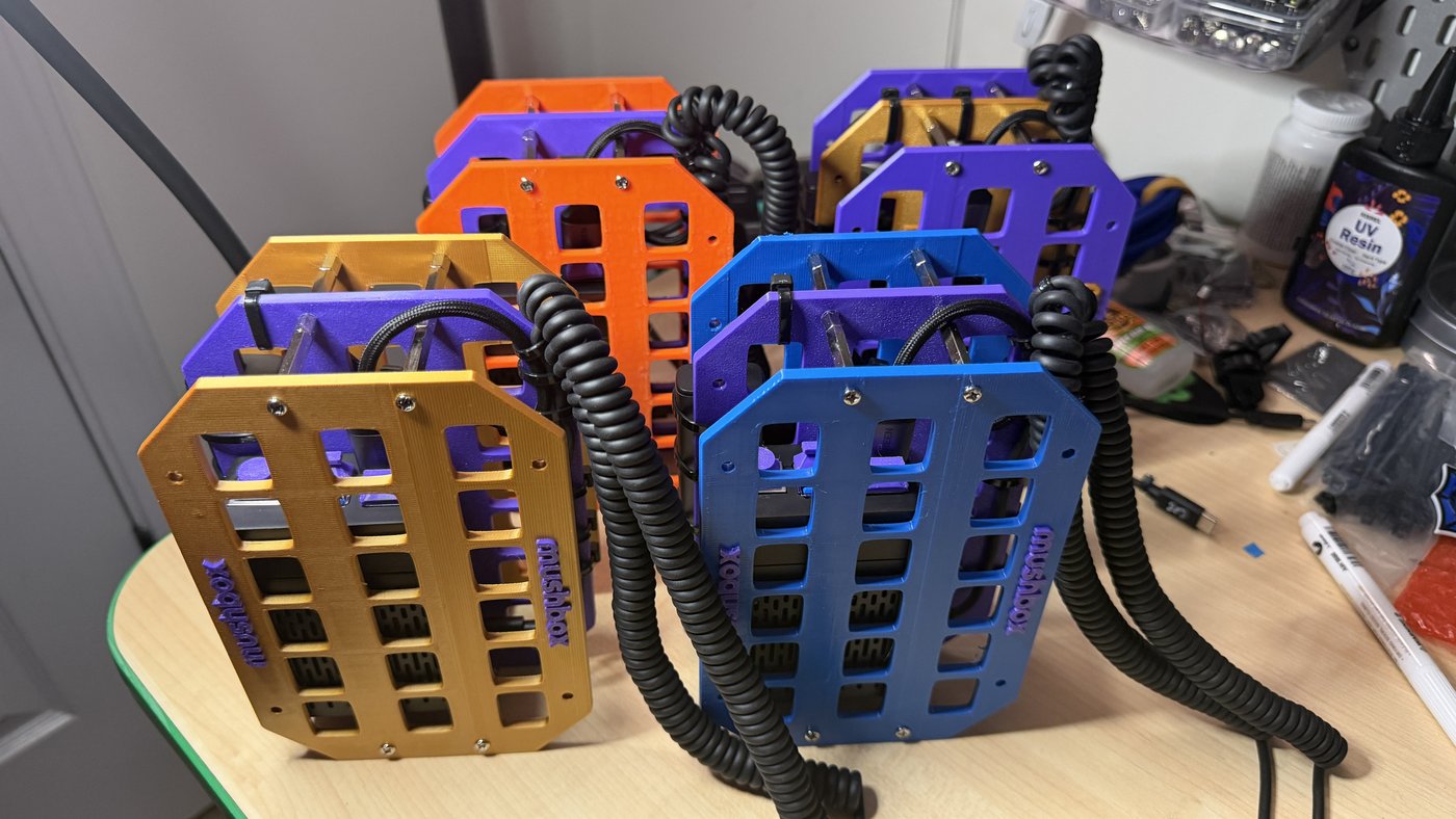 Batch of Mushbox builds in gold, orange, purple, and blue colorways on the workbench